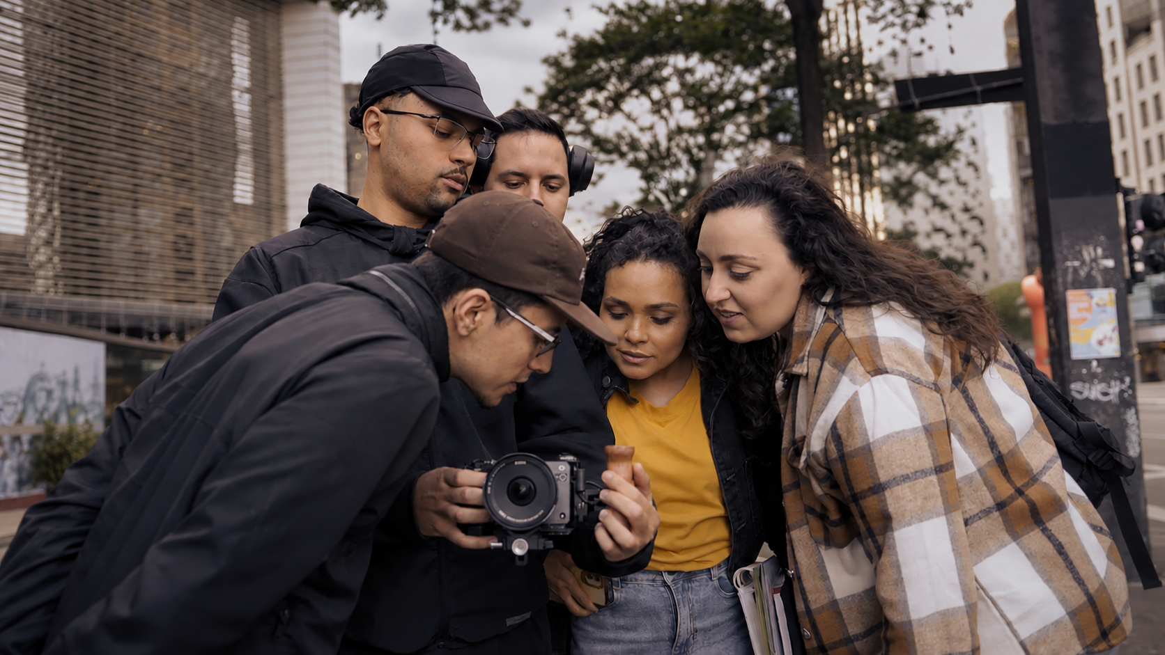 Equipe da Merx Media House reunida em volta do monitor de vídeo durante uma captação em rua de São Paulo, céu nublado
